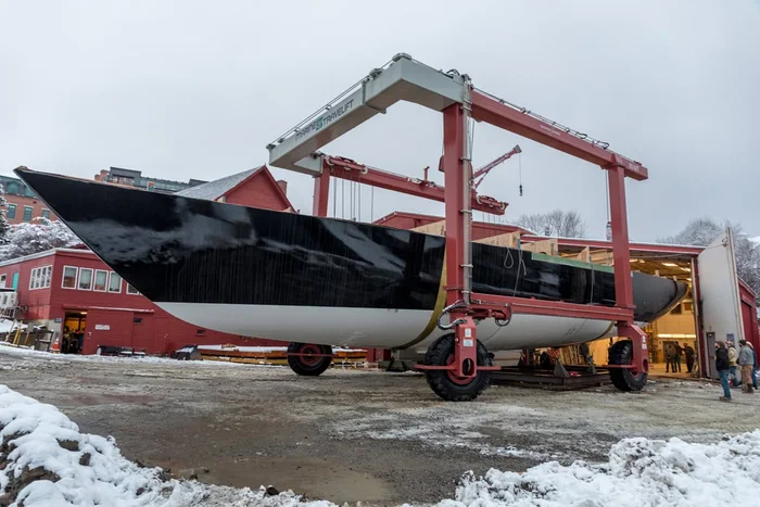 Ouzel's black hull carried in the yard's travel hoist.