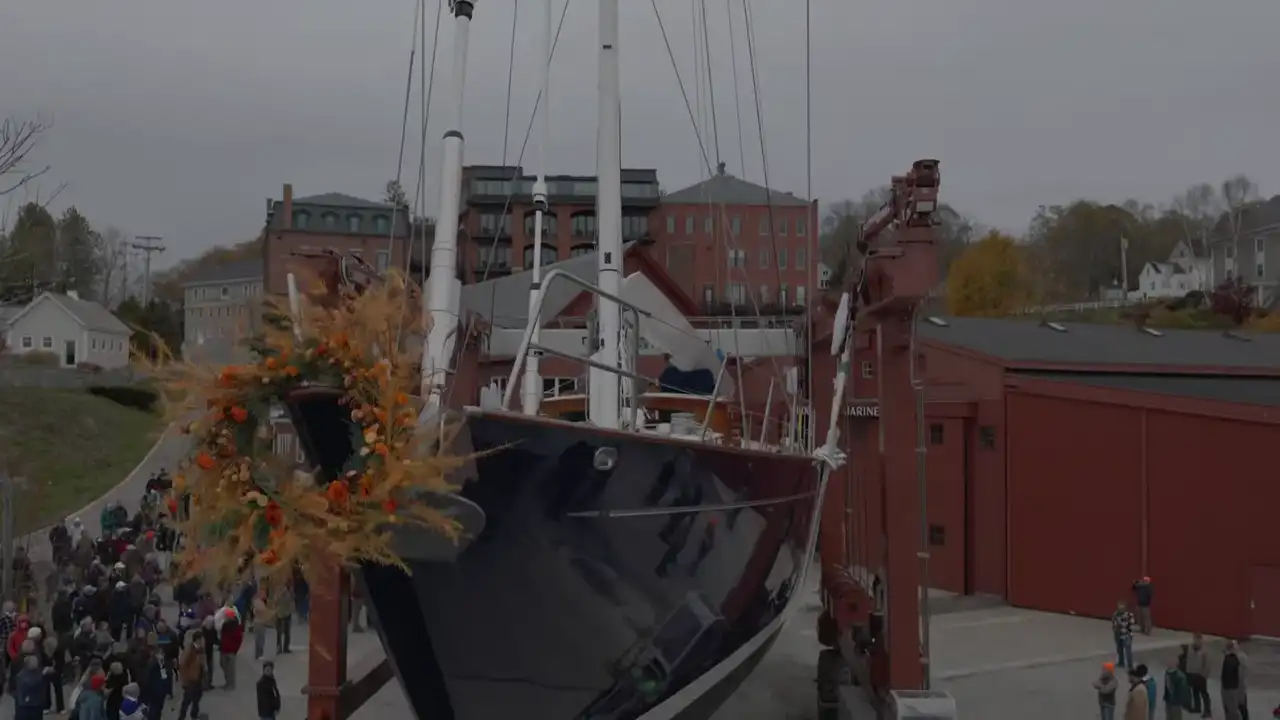 The 95-foot yacht Ouzel on the launch railway at Rockport Marine, an autumn garland on her bow, the yard crowd along the rails.